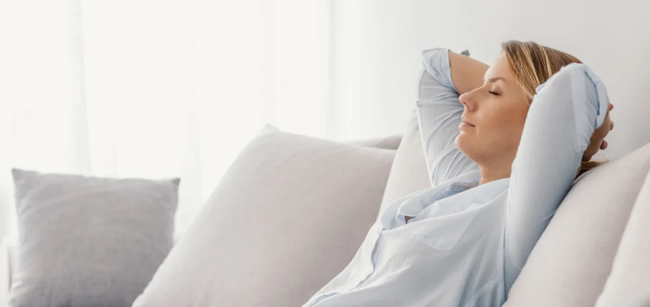 Profi-Service - eine Frau sitzt entspannt auf einem Sofa im Wohnzimmer, die Hände hinter dem Kopf verschränkt