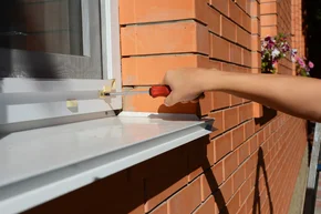 Nachrüstung - Handwerker montiert ein Moskitonetz, Insektenschutz auf Backsteinhausfenster.