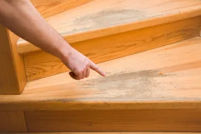 Hand zeigt mit dem Finger auf alte zerschlissene Holztreppe, Treppenrenovierung - Hand zeigt mit dem Finger auf alte zerschlissene Holztreppe, Treppenrenovierung