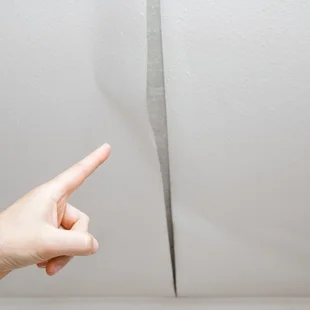ansatzfrei - Mannes Hand Fingerzeig auf das Problem. Alte Tapete von der Decke in den Raum abziehen. - Stock-Fotografie